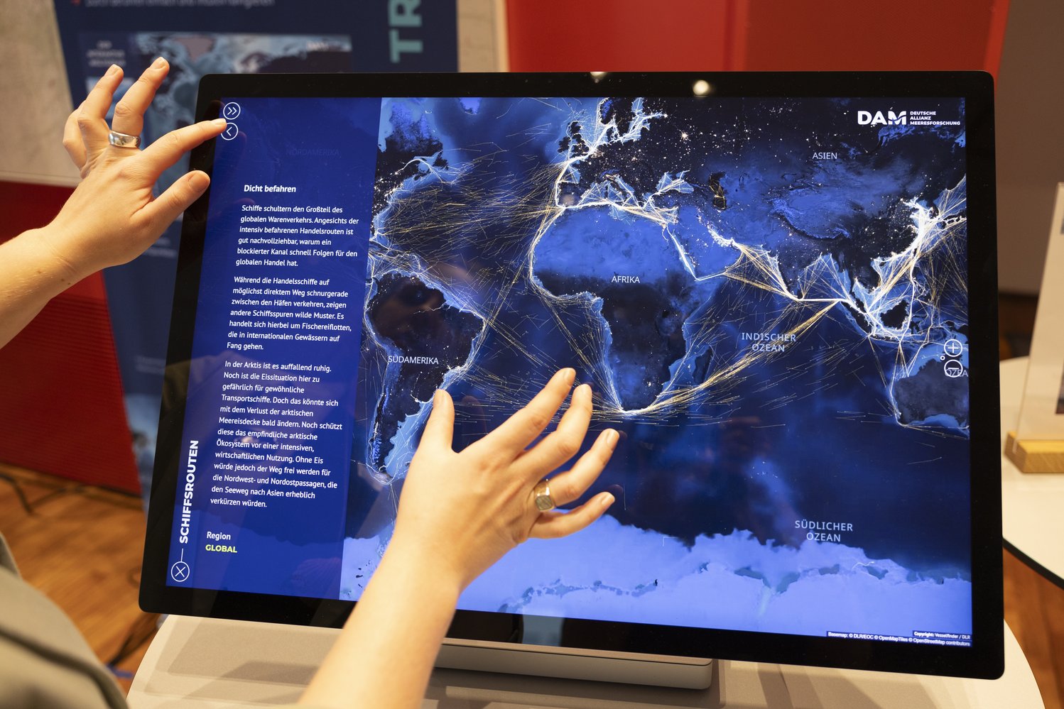 Zwei Hände berühren einen Touchdisplay und interagieren mit dem Interaktiven Weltozean.