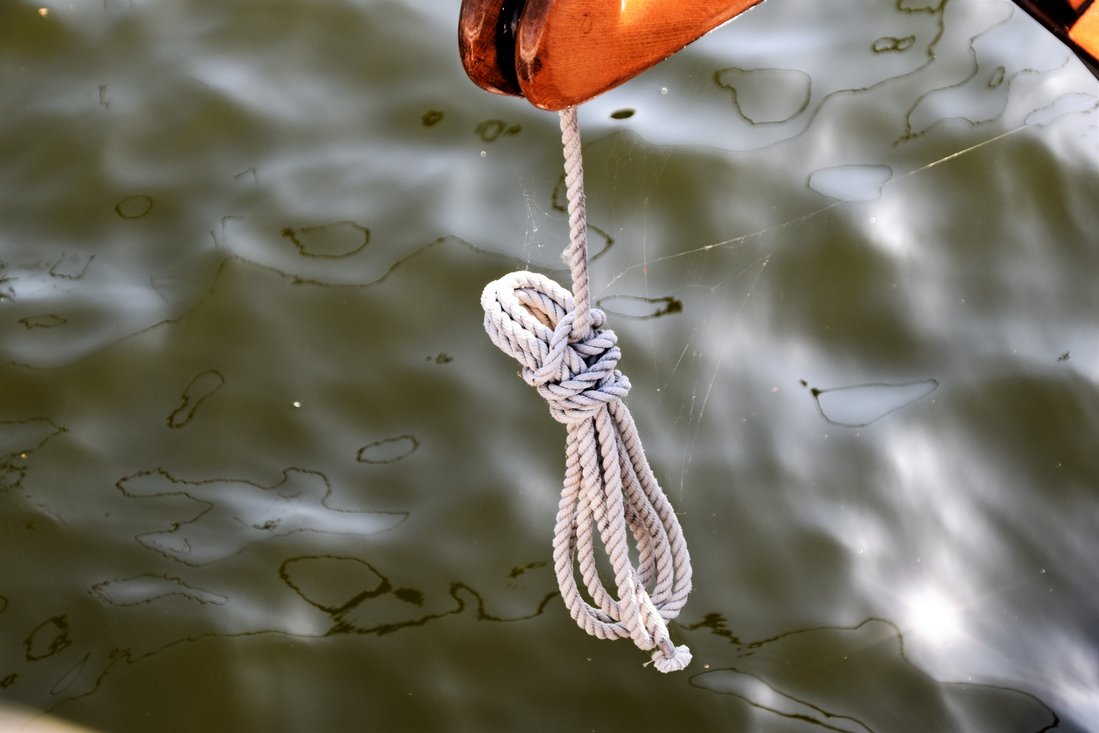 Seil am Segegelboot hängt über Wasser mit Ölfilm-Flecken.Foto von Waldemar auf Unsplash.